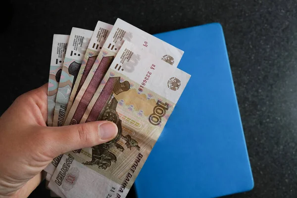 Een werknemer houdt bankbiljetten in coupures van 100 en 50 roebel. — Stockfoto