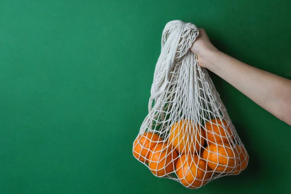 Manzanas en una bolsa de hilo en las manos sobre un fondo verde. — Foto de Stock