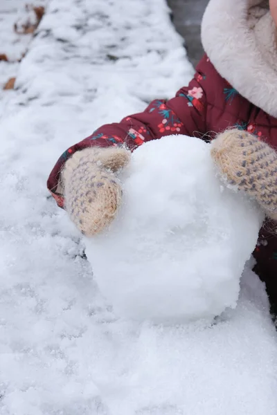 Il bambino tiene in mano una palla di neve. Immagine con messa a fuoco morbida. — Foto Stock