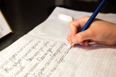 Çocuk not defterine kurşun kalemle mektup ve kelime yazmayı öğreniyor. 