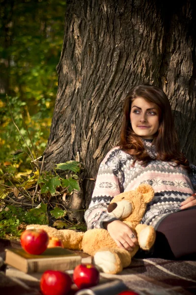Girl posing in the forest in autumn with a teddy bear — Stock Photo, Image