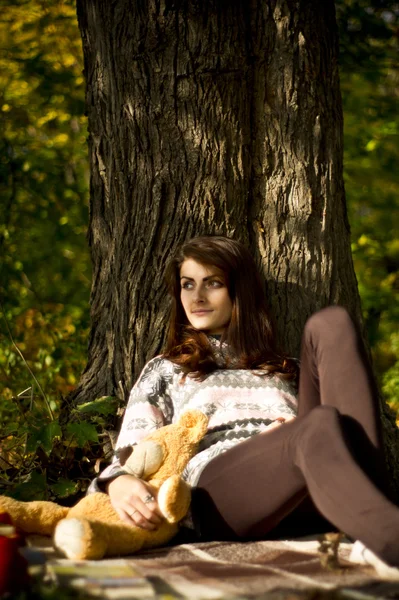 Girl posing in the forest in autumn with a teddy bear — Stock Photo, Image