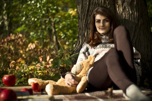 Flicka som poserar i skogen under hösten med en nallebjörn — Stockfoto