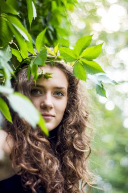 çekici kız gülümseyerek yaprakları ile duvara duruyor