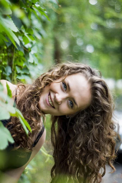 Chica atractiva está de pie contra la pared con hojas sonriendo —  Fotos de Stock