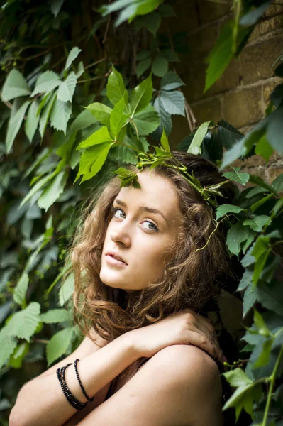 Attrayant fille est debout contre le mur avec des feuilles souriantes — Photo