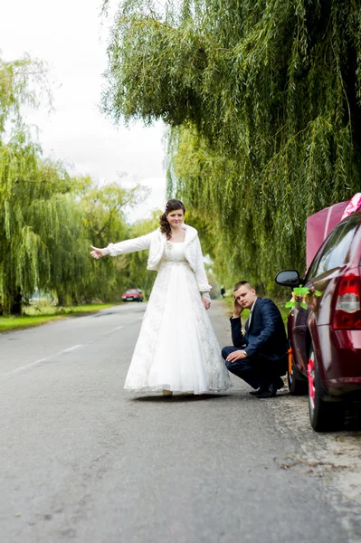 The bride and groom stopped the car near his broken car — Stock Photo, Image