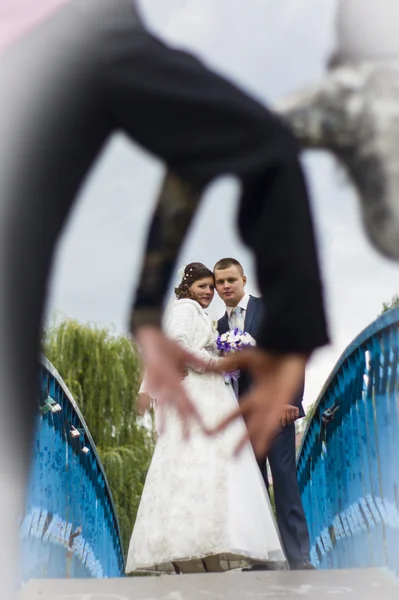 Ο γαμπρός και η νύφη με τα πόδια στο φθινόπωρο πάρκο σε ένα πλαίσιο σε σχήμα καρδιάς, φτιαγμένο από χέρι — Φωτογραφία Αρχείου