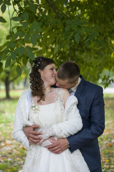 De bruidegom en de bruid op wandeling in de herfst park kussen — Stockfoto