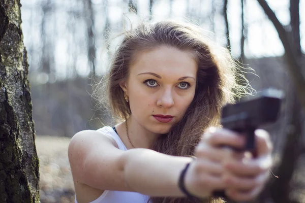 Beautiful young woman holding an automatic assault rifle — Stock Photo, Image