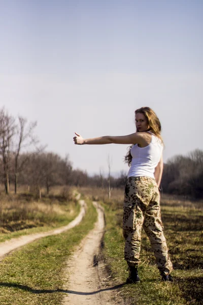 Beautiful young woman holding an automatic assault rifle — Stock Photo, Image