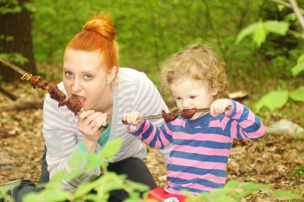 Moeder eet en leert om te eten van gegrild vlees op de grill zijn dochter — Stockfoto