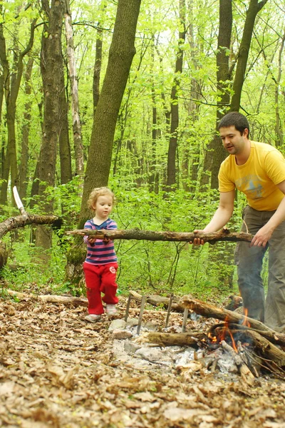 Táta holčička pomáhá zapálit oheň v lese — Stock fotografie