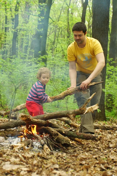 Táta holčička pomáhá zapálit oheň v lese — Stock fotografie