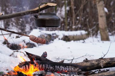 Çubuktaki sosisler ateşte kızardı. Kış Ormanı.