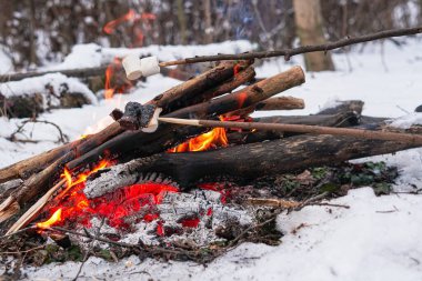 Kış ormanında ateşte kavrulmuş şekerlemeler.