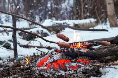 Çubuktaki sosisler ateşte kızardı. Kış Ormanı.
