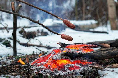 Çubuktaki sosisler ateşte kızardı. Kış Ormanı.