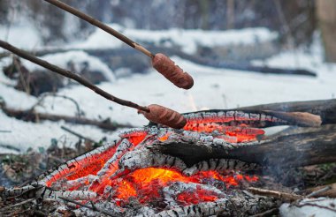 Çubuktaki sosisler ateşte kızardı. Kış Ormanı.