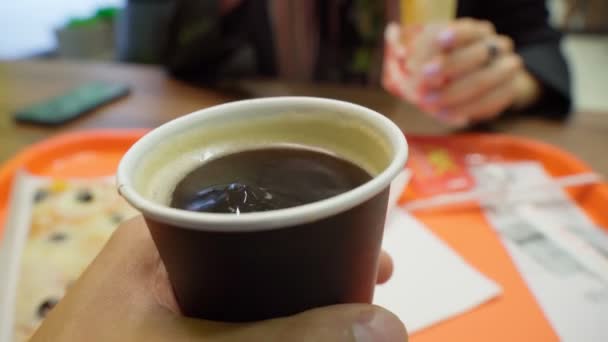 Bir fincan yakın çekim kahve. Bir adam fast food restoranında kağıt bardak tutuyor. Seçici odak — Stok video