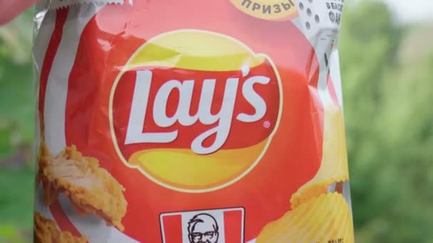 Volzhsky, Rusia-25 de septiembre de 2021: Lays une sus manos con el nuevo sabor de KFC. Pollo frito y ala de pollo. Enfoque selectivo — Vídeos de Stock