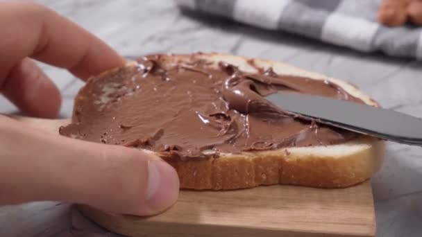 早餐期间，用抹过的巧克力黄油切碎的白面包，用可可可豆做的天然巧克力酱 — 图库视频影像