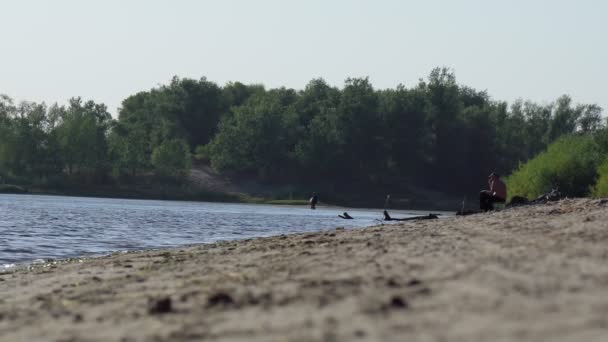 Volzhsky, Rusya-23 Eylül 2021: Bir balıkçı nehir kıyısında oturur ve yazın balık tutar. — Stok video