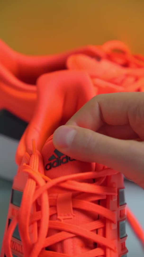 Tyumen,ロシア- 2021年11月13日: Adidasランニングシューズ,オレンジ色のサンゴ色, eq21ラン.ロゴ。垂直ビデオ — ストック動画