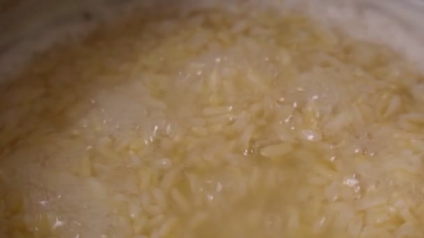 Cuire le riz brun dans une casserole en gros plan. La cuisson est un objectif sélectif. Mouvement lent — Video