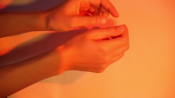 Hands of a man on a multicolored background from a colored lamp. Selective focus — Stock Video