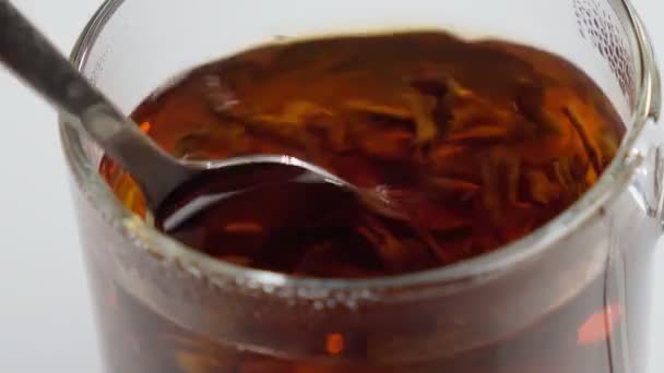 Aufgebrühter Tee, ein Glas Tee mit selektivem Fokus, Nahaufnahme. Mit einem Löffel umgerührt — Stockvideo