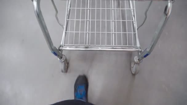 Pulling a shopping cart in a grocery store. Buying groceries in a hypermarket — 图库视频影像