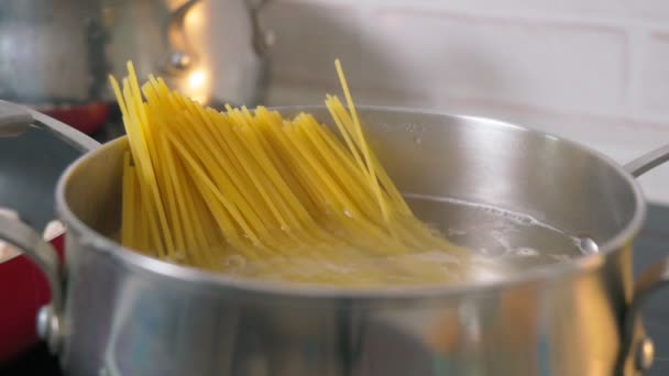 Gros plan sur les pâtes spaghetti dans de l'eau bouillante chaude dans une casserole en acier. Cuisine à la maison, journée spaghetti — Video