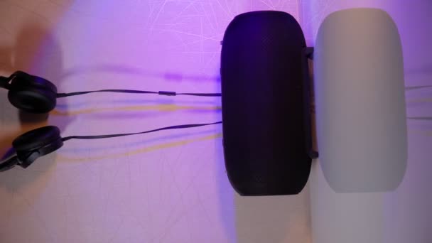 Μαύρα ενσύρματα ακουστικά με ασύρματο ηχείο σε πολύχρωμο φόντο. Κάθετη βίντεο — Αρχείο Βίντεο