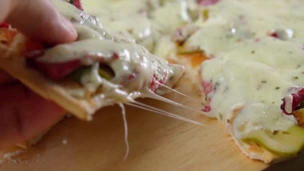 Hand neemt een plakje gesneden pizza met Mozzarella kaas, tomaten, peper. Langzame beweging — Stockvideo