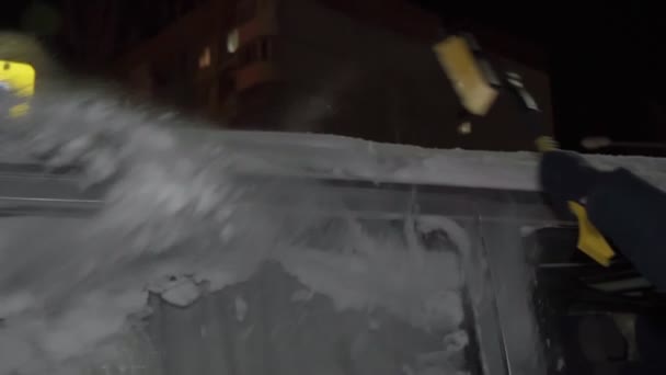 Remoção de neve no inverno do carro à noite. Foco seletivo. Movimento lento — Vídeo de Stock