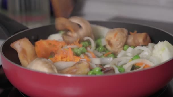 Cooking vegetables in a frying pan, mushrooms, peas, onions, carrots. Selective focus — Stockvideo