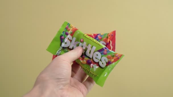 Tyumen, Russia-December 27, 2021: Skittles candies made by Wm. Wrigley Jr. Company. yellow background — стоковое видео