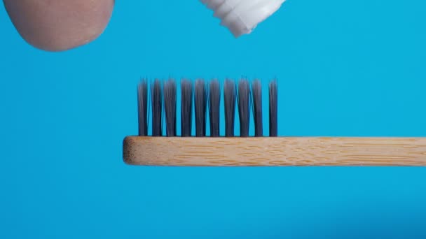 歯ブラシは竹で作られた環境に優しいです。歯磨き粉を閉じます。ゴミゼロの家。青の背景 — ストック動画
