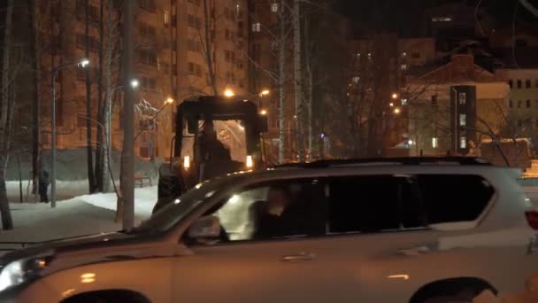 Tyumen, Rusia-24 de diciembre de 2021: Arado de nieve en la carretera por la noche, limpiando la calle de la ciudad de la deriva de nieve después de fuertes nevadas. Enfoque selectivo — Vídeos de Stock