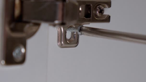 Twists the self tapping screw to install the hinge in the furniture door from the cabinet. Close-up selective focus — Stock Video