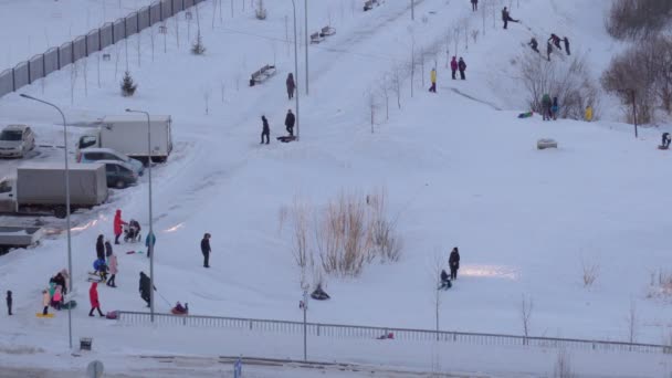 Tyumen, Oroszország-január 23, 2022: Az emberek lefelé lovagolnak télen, a szülők játszanak a gyerekekkel, felülnézet — Stock videók