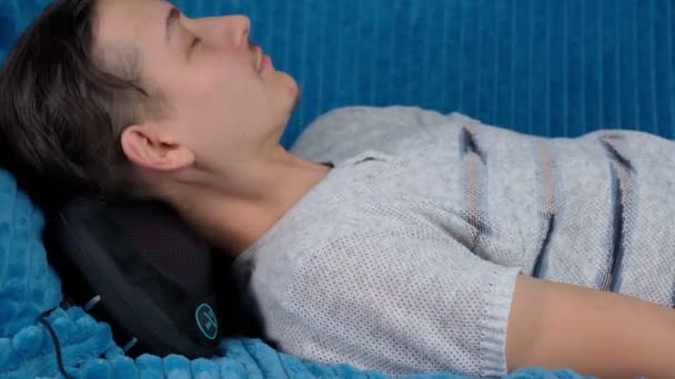Cojín de masaje eléctrico con zonas de calentamiento por infrarrojos. Milineal hombre se relaja en casa — Vídeos de Stock