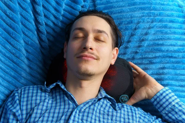 A man massages neck with a massage pillow, body feel more relaxed