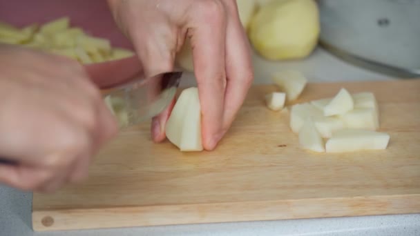 Картофель нарезать небольшими кусочками. Крупный план рук повара во время работы на кухне — стоковое видео