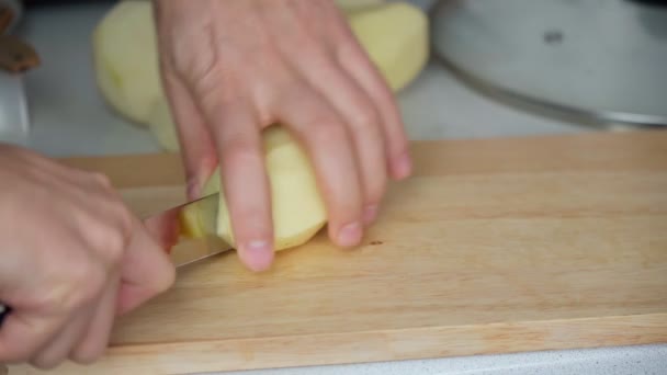 Mänskliga händer skär råpotatis i skivor med vass kökskniv på träskärning. Tillagning vegetarisk hälsosam mat. Hemlagad mat. — Stockvideo