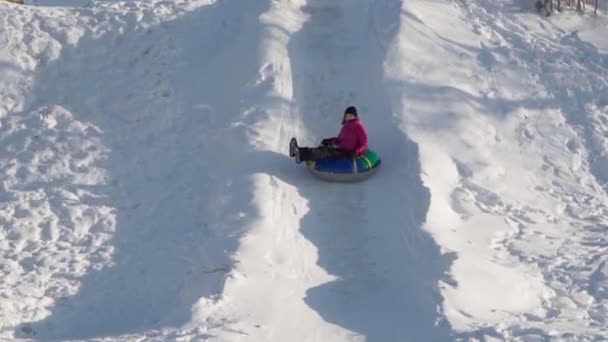 Mulher monta um tubo de neve enquanto tubulação em um parque de inverno. Temporada de inverno, câmera lenta — Vídeo de Stock