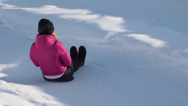 Una ragazza cavalca un tubo da uno scivolo in inverno in una nevicata. Tubi, sport invernali all'aperto. Rallentatore — Video Stock