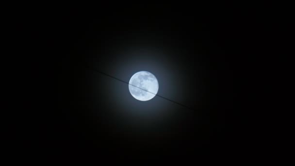 La luna llena es azul sobre el fondo del cielo negro nocturno, un cable colgante de los edificios — Vídeos de Stock