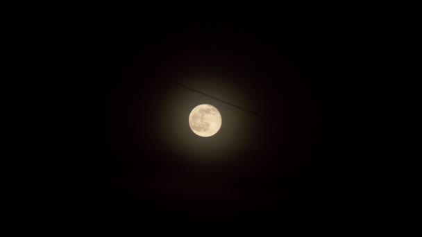 캄캄 한 검은 밤하늘을 배경으로 한 보름달을 가까이 서 찍었습니다. 전기선, 밤에 도시 — 비디오